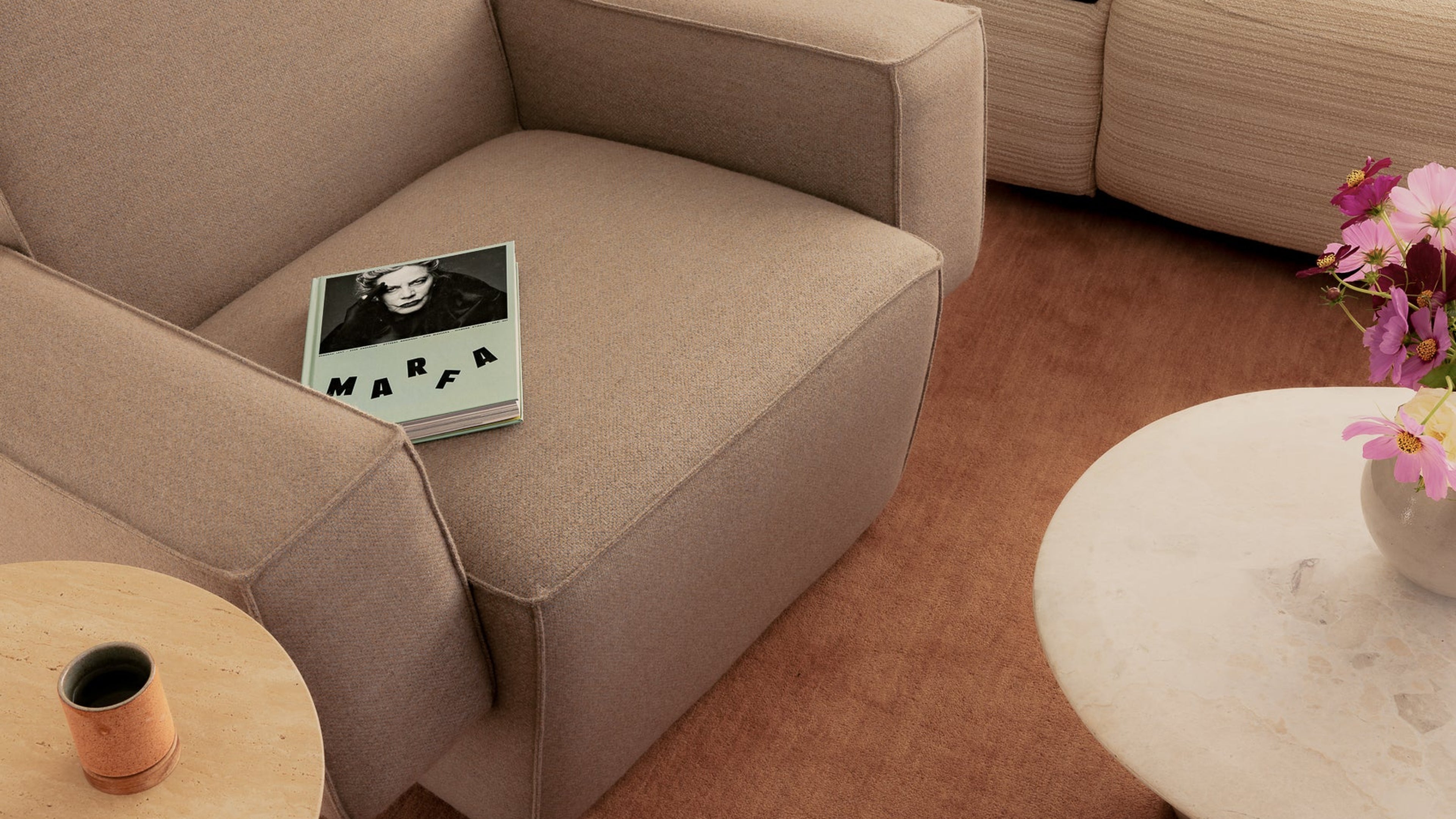 Beige sofa with a magazine titled 'Marfa' on it, surrounded by a cozy living room setting.