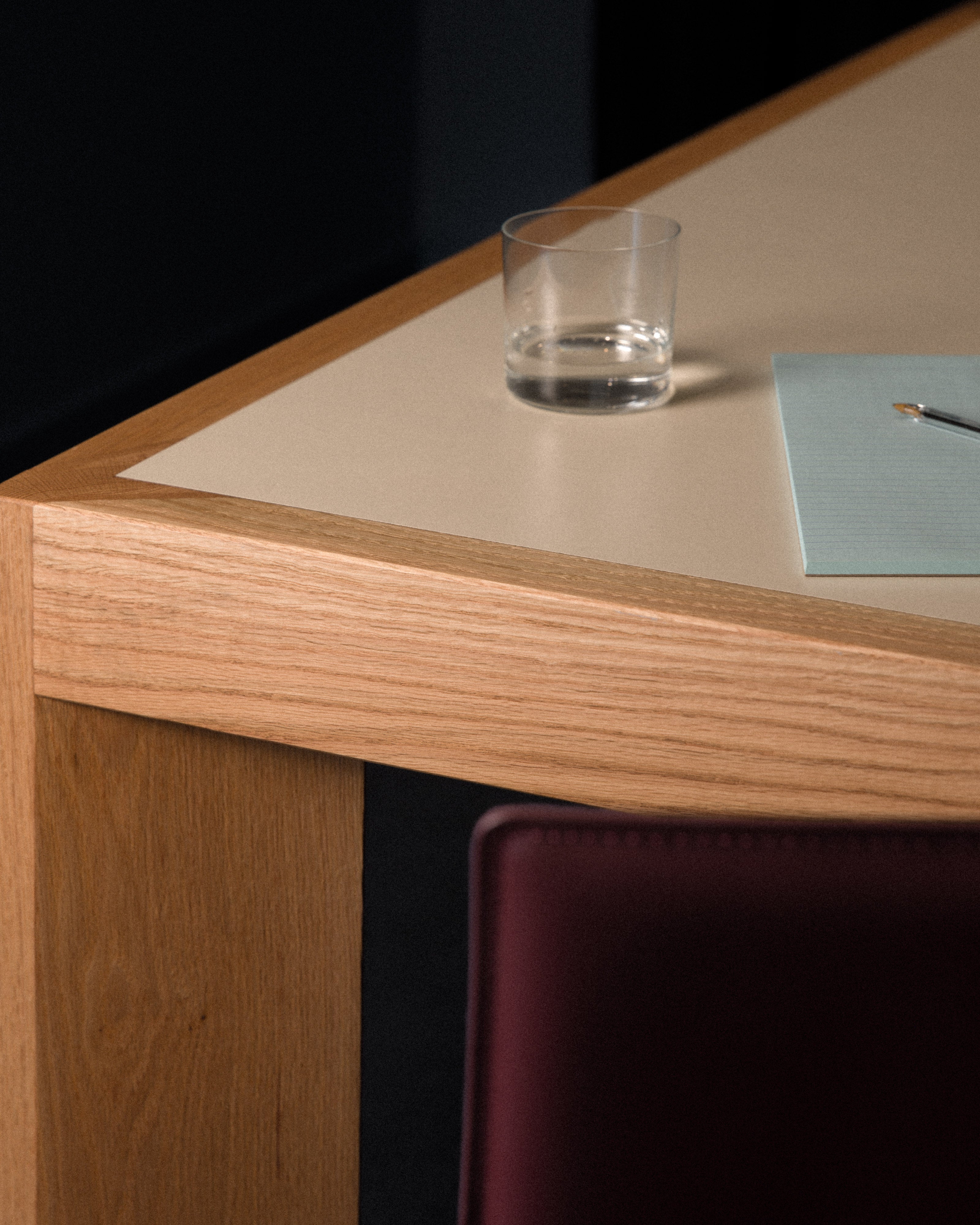 Close-up detail of oak-framed conference table with cream insert, glass of water, and pen in a styled commercial boardroom interior — commercial office interior design detail by Studio Nicholas Noosa Queensland Australia
