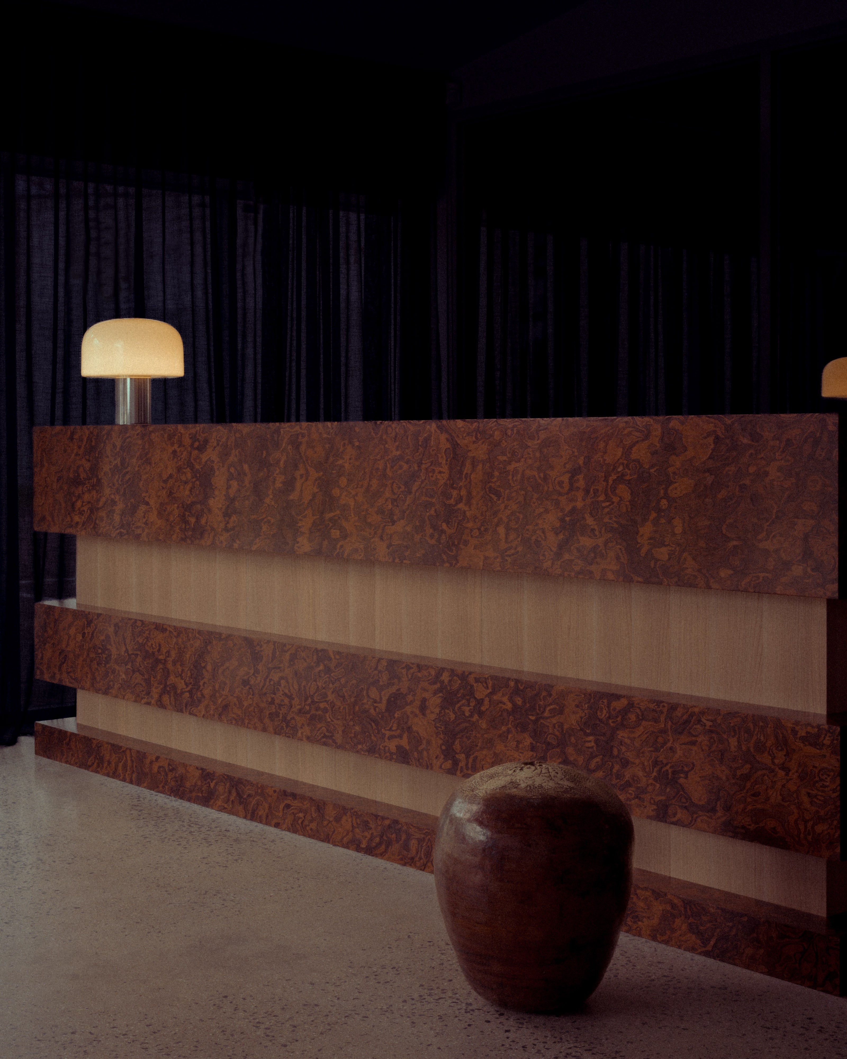 Burl wood veneer reception desk with natural oak inlay detail and handcrafted ceramic vessel and lamp — luxury commercial interior design detail by Studio Nicholas Noosa Queensland Australia