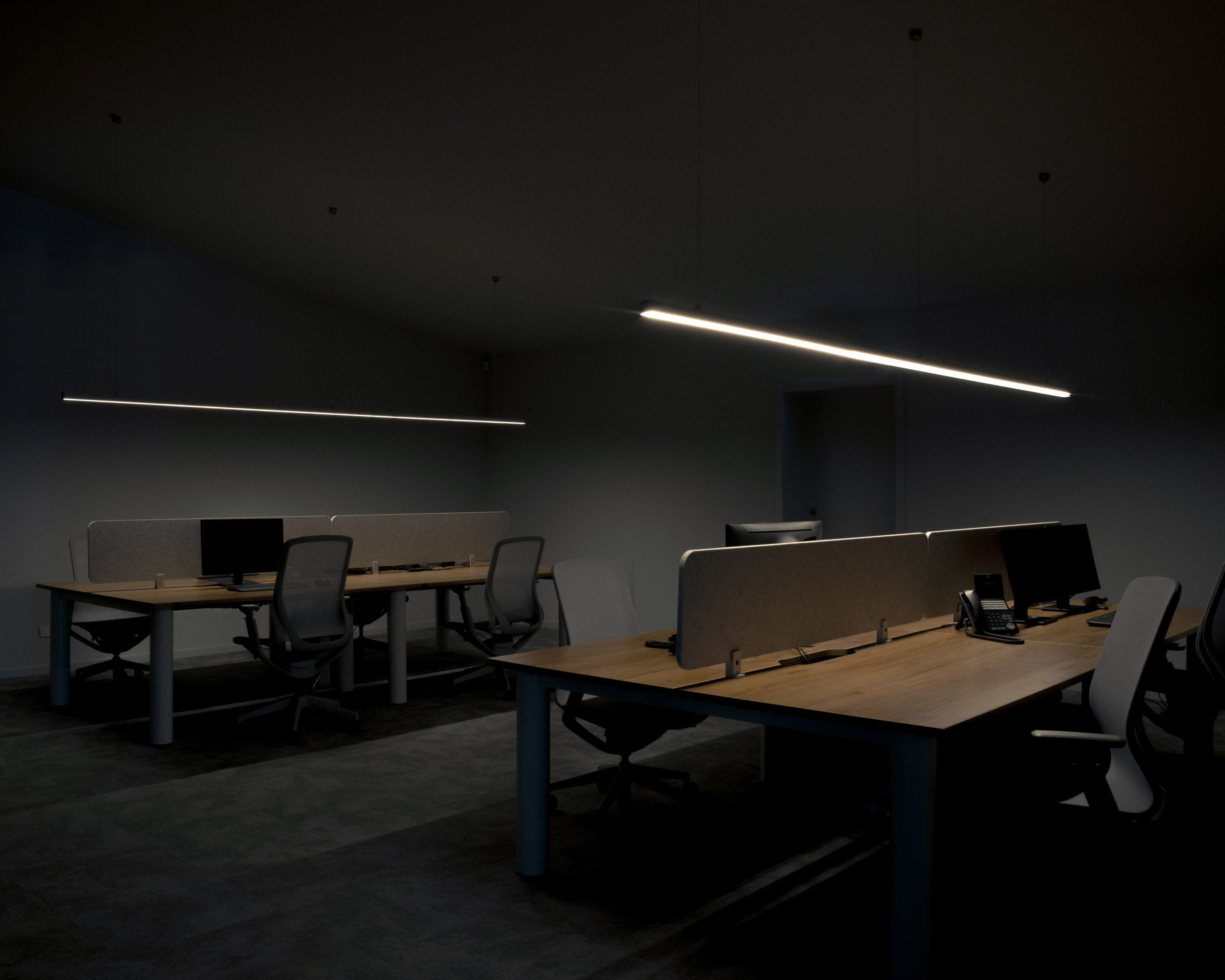 Wide moody commercial office fit-out with rows of back-to-back workstations, timber and blue desks, acoustic dividers, ergonomic task chairs, monitors, and linear LED pendant lighting — commercial interior design by Studio Nicholas Noosa Queensland Australia